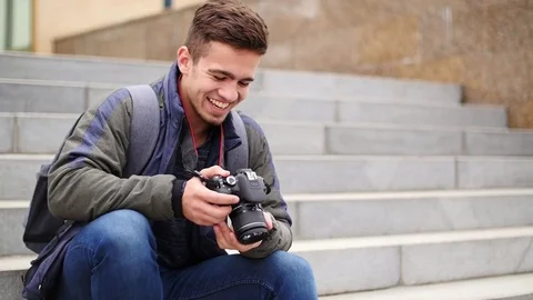 Young guy looks at the digital camera while in the city Stock Footage 81219807