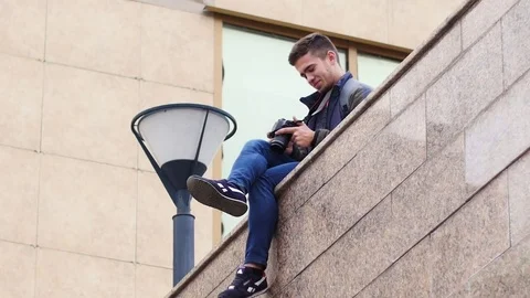 Young guy looks at the digital camera while in the city Stock Footage 81220495