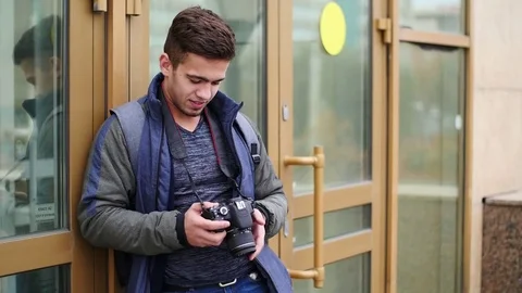 Young guy looks at the digital camera while in the city Stock Footage 81221183