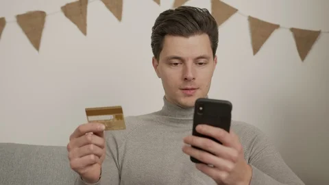 A young guy make shopping online. Enters data from credit card. Video stock 121312409