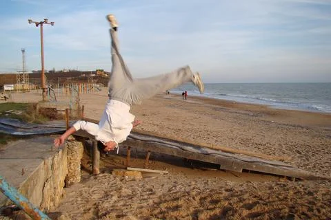 A young guy makes an acrobatic jump on the sea Photos