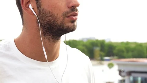 A young guy makes a sound in his headphones louder Stock Footage 82058431