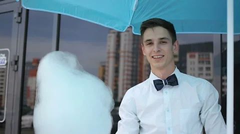 Young guy making cotton candy on a special machine, it wears bow tie, behind him Stock Footage 64043237