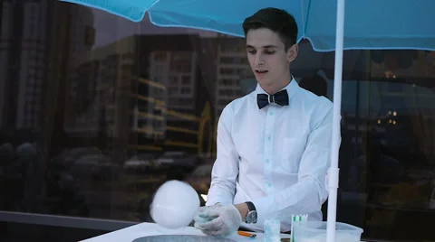 Young guy making cotton candy on a special machine, it wears bow tie, behind him Stock Footage 64043267