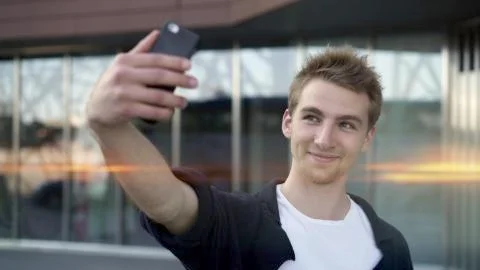 Young guy making selfie on background of glass business building, lens flare Fotos de archivo