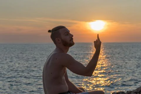 Young guy with a man bun balancing the Sun on his finger Stock Photos