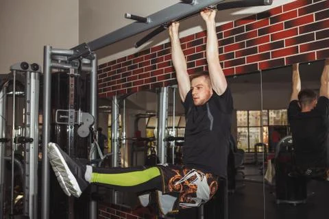 A young guy, a man pulls himself up on a crossbar in the gym. Performs weight Stock Photos