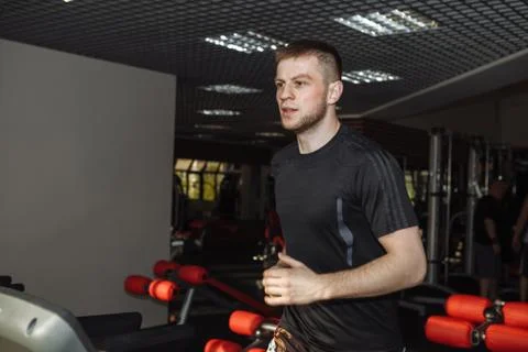 A young guy, a man is running on a treadmill in the gym. Stock Photos