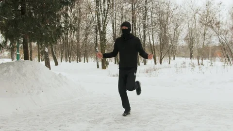 Young guy in a mask on his face, in a black sports suit, performing exercises Vidéo 108832345