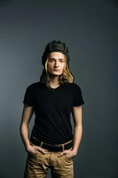Young guy model posing in a tankman helmet on the gray background. hands in p Stock Photos