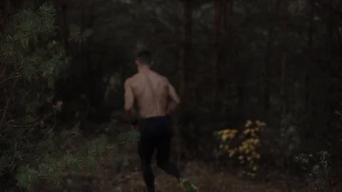 Young Guy With Naked Torso Completes Jogging In The Forest. Slow motion Видео 125855271