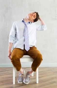 Young guy office worker doing exercises on chair Stock Photos