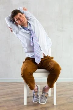 Young guy office worker doing exercises on chair Stock Photos