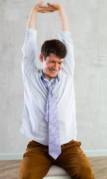 Young guy office worker doing exercises on chair Stock Photos