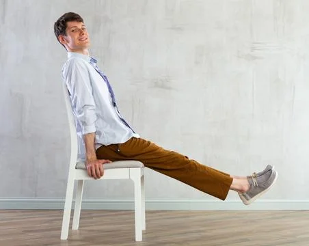 Young guy office worker doing exercises on chair Stock Photos