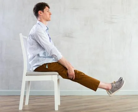 Young guy office worker doing exercises on chair Foto stock