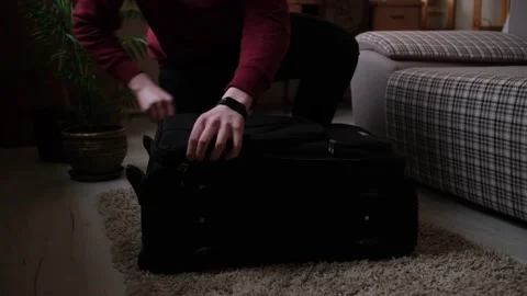 A young guy opens a suitcase and collects things in a hurry because of the hosti Stock Footage 170875436
