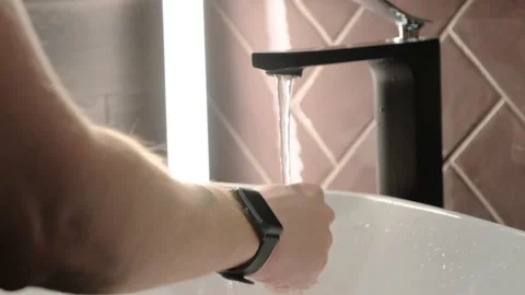 A young guy opens the tap with water in the sink and washes his hands. 스톡 동영상 138998704