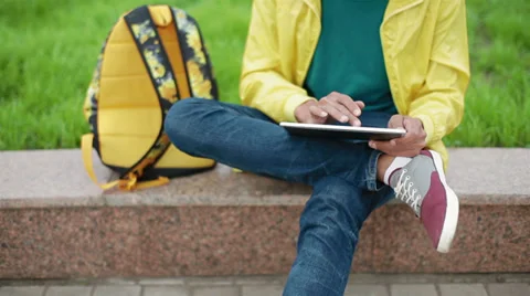 Young guy with original appearance sitting in the park and enjoys tablet Stock-Footage 38337016