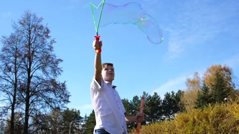 A young guy in the park makes big soap bubbles. Holiday and outdoor Видео 95894530