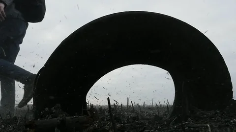 Young guy passes near the rubber tire on the burnt ground in the field after a Stock Footage 105545259