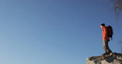 Young guy on the peak of the cliff is raising his hands at the sky background Stock Footage 106085950