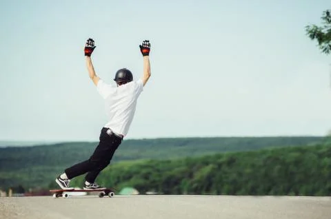 A young guy performs a complex trick on the longboard Stock Photos