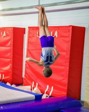 A young guy performs a jump somersault, in training. Stock Photos