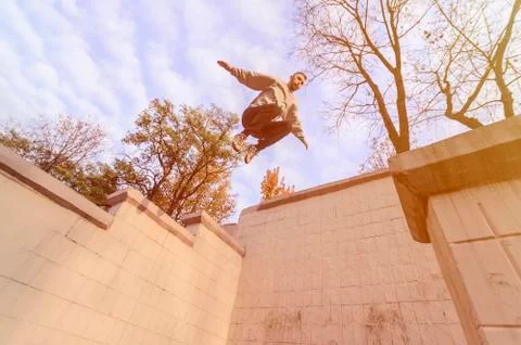 A young guy performs a jump through the space between the concrete parapets.  写真素材