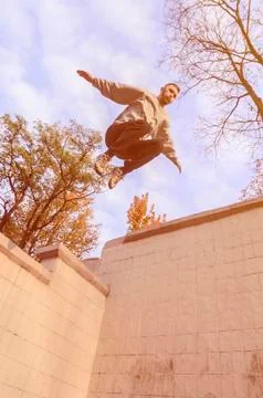 A young guy performs a jump through the space between the concrete parapets.  写真素材