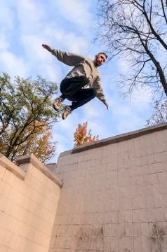 A young guy performs a jump through the space between the concrete parapets.  写真素材