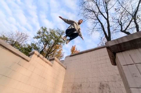A young guy performs a jump through the space between the concrete parapets.  写真素材