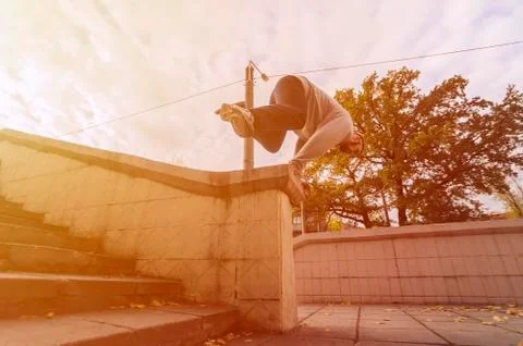A young guy performs a jump through the concrete parapet. The athlete practic Foto stock