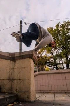 A young guy performs a jump through the concrete parapet. The athlete practic Foto stock