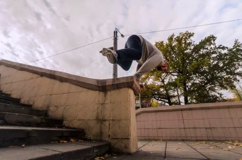 A young guy performs a jump through the concrete parapet. The athlete practic Stockfoto's