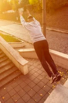 A young guy performs a jump through the space between the concrete parapets.  写真素材
