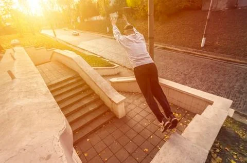 A young guy performs a jump through the space between the concrete parapets.  写真素材