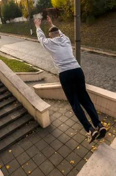 A young guy performs a jump through the space between the concrete parapets.  写真素材