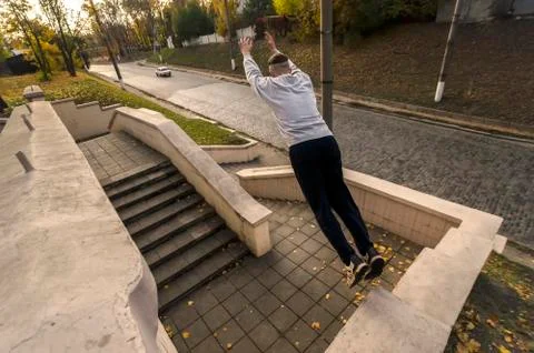 A young guy performs a jump through the space between the concrete parapets.  写真素材