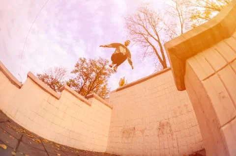 A young guy performs a jump through the space between the concrete parapets.  写真素材