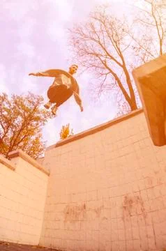 A young guy performs a jump through the space between the concrete parapets.  写真素材