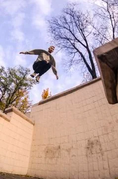 A young guy performs a jump through the space between the concrete parapets.  写真素材