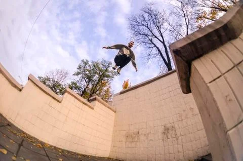 A young guy performs a jump through the space between the concrete parapets.  写真素材