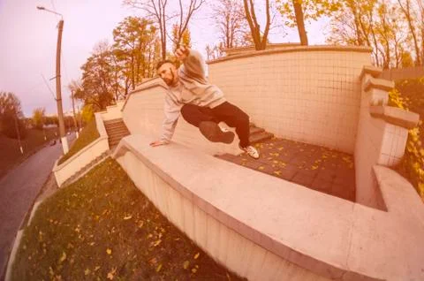 A young guy performs a jump through the concrete parapet. The athlete practic Foto stock