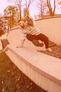 A young guy performs a jump through the concrete parapet. The athlete practic Foto stock