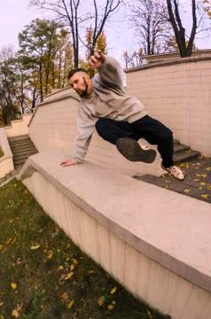 A young guy performs a jump through the concrete parapet. The athlete practic Foto stock