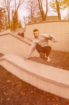 A young guy performs a jump through the concrete parapet. The athlete practic Foto stock