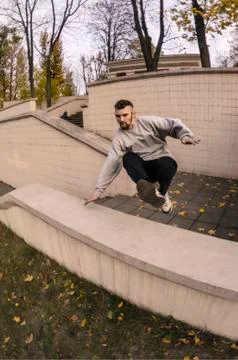 A young guy performs a jump through the concrete parapet. The athlete practic Foto stock