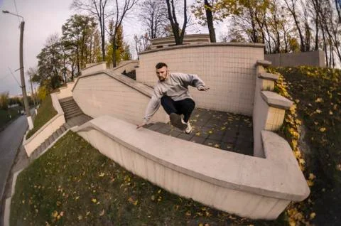 A young guy performs a jump through the concrete parapet. The athlete practic 写真素材