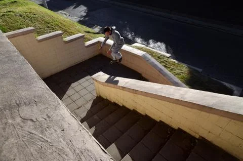 A young guy performs a jump through the space between the concrete parapets.  写真素材